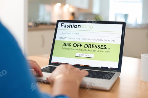 Preview: Online Shopping Experience in a Cozy Kitchen With a Laptop Displaying Discounts on Dresses