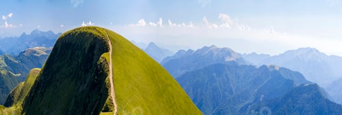 Preview: Panorama of green hills in summer mountains with gravel road for travelling by car