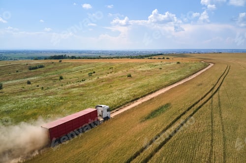 Preview: Aerial view of lorry cargo truck driving on dirt road between agricultural wheat fields.