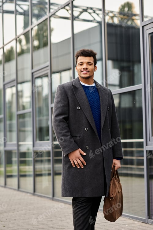 Preview: Handsome man in sophisticated coat walking in a modern urban area on a sunny day