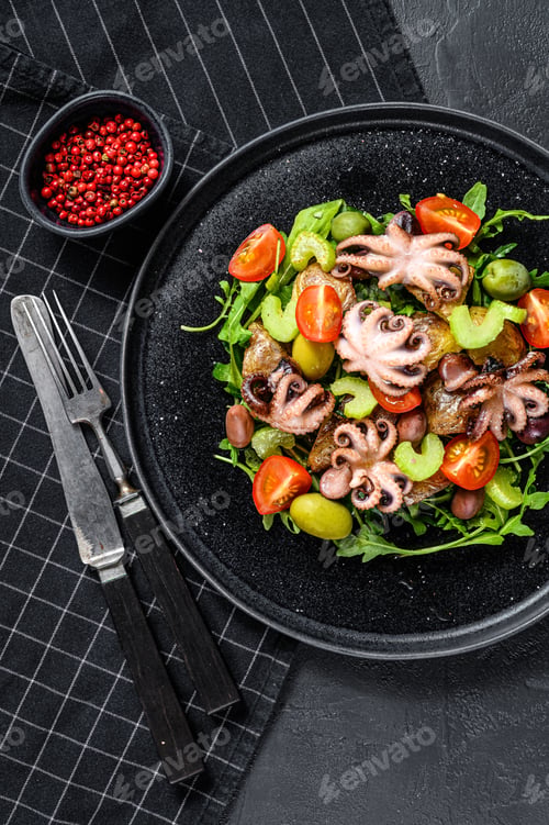 Preview: Homemade salad with octopus and potatoes, arugula, tomatoes and olives. Black background. Top view