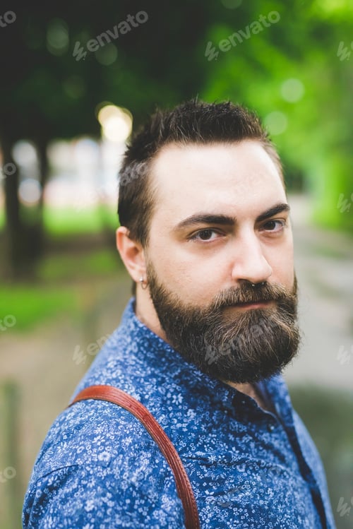 Preview: Man with a confident gaze in a tranquil urban park setting.