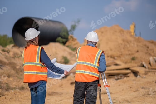 Preview: Construction surveyor or engineer working construction site blueprint and theodolite mounted tripod