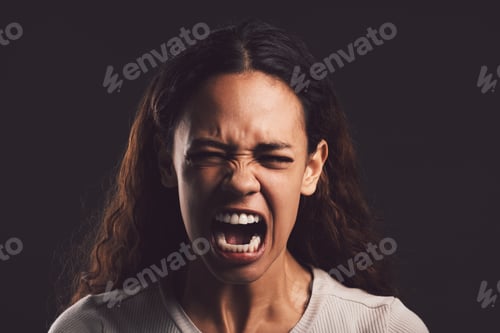 Preview: Shot of a young woman experiencing mental anguish and screaming against a black background