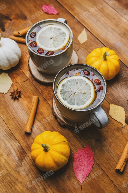 Preview: Warm drinks with lemon and berries in cups with pumpkins and cinnamon sticks on wood