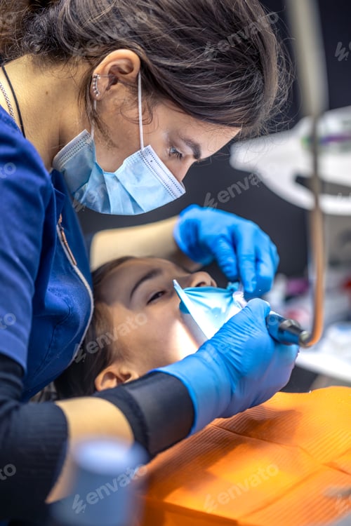 Preview: The dentist treats the child's tooth using a rubber dam. Close-up of tooth treatment.