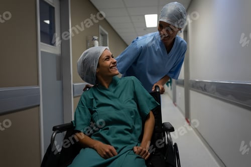 Preview: Female patient on wheelchair talking with female surgeon in the hospital corridor