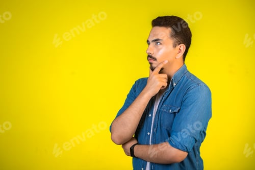 Preview: Man holding his chest and planning further steps on yellow background