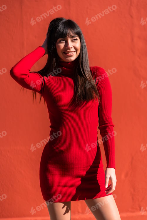 Preview: Posed brunette girl in a dress in spring. Caucasian pretty a red background