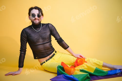 Preview: Handsome young man with pride movement LGBT Rainbow flag on shoulder against white background.