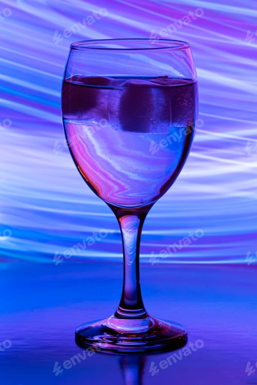 Preview: wine glass with ice on black backgound with neon light painings behind