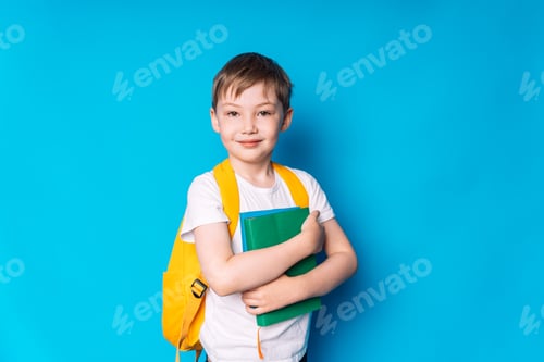 Preview: Boy with a yellow backpack and a book in his hands against a blue background