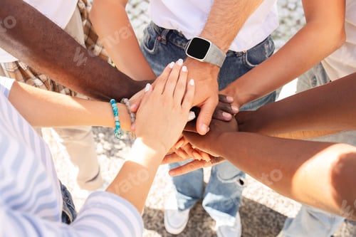 Preview: Multicultural people holding hands on top each other, cropped
