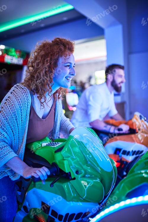 Preview: Woman playing and having fun with a driving simulator in an amusement arcade