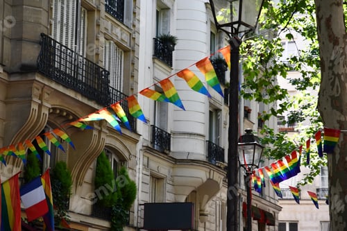 Preview: Bright garlands of striped triangle banners in colors of LGBTQ flag on street of Paris France