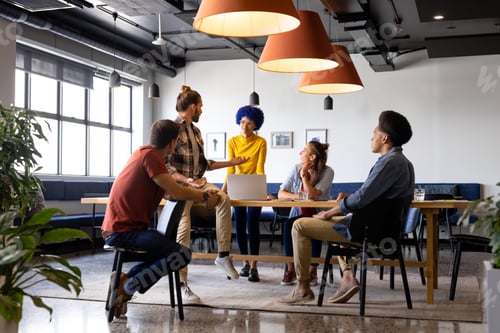 Preview: Diverse male and female colleagues using laptop in casual office meeting