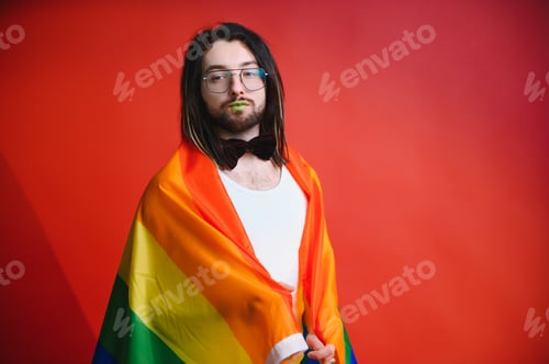 Preview: Gay man hold rainbow striped flag isolated on colored background studio portrait.