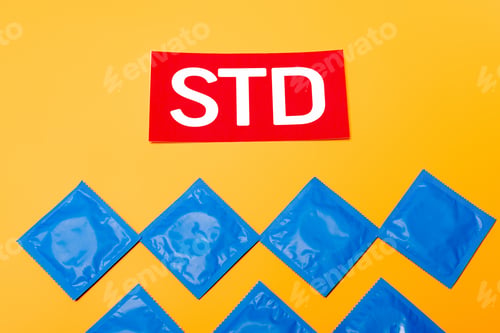 Preview: top view of packs with condoms near red std lettering isolated on orange