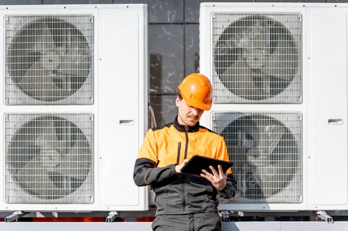 Preview: Workman servicing air conditioning or heat pump with digital tablet