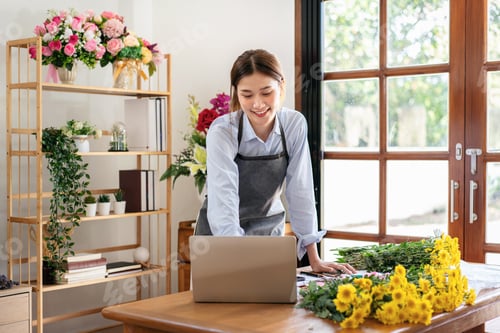 Preview: Female florist in apron using laptop to working and receive cust