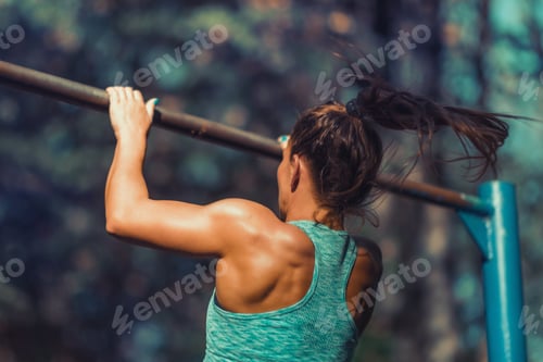 Preview: Woman Exercising on Horizontal Bar Outdoors in The Fall