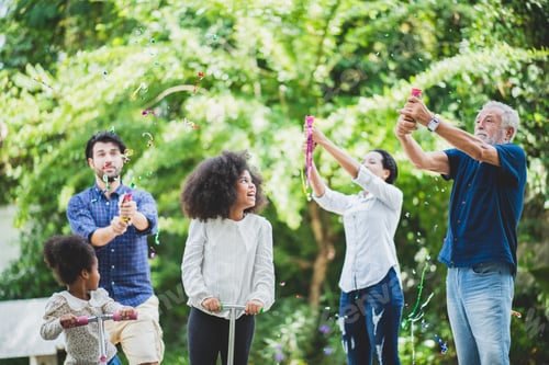 Preview: Cheerful family of grandfather, mother and father blowing sparkles at grandchildren on completing