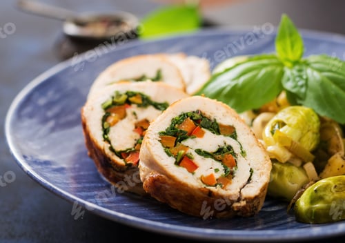 Preview: Chicken rolls with greens, garnished with stewed Brussels sprouts, apples and leeks on a blue plate.