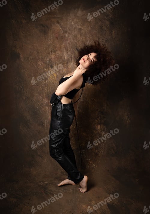 Preview: Beautiful Caucasian female model with afro hair posing in front of a brown background