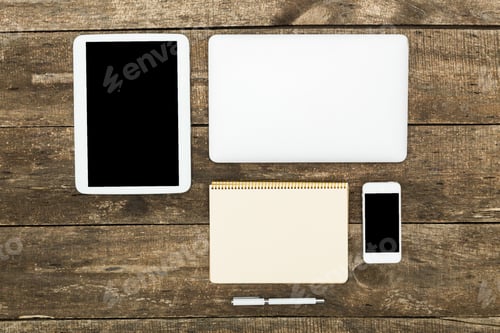 Preview: Collection of electronic devices and stationery arranged on wooden table during daytime