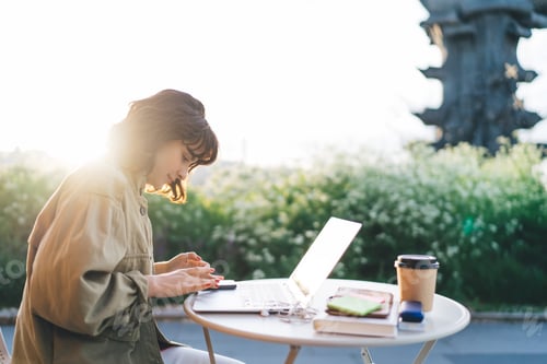Preview: Focused woman using smartphone working in outdoor cafe