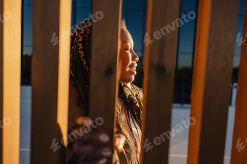 Preview: african woman clinging to the fence sunset
