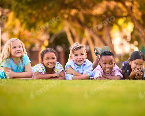 Preview: Portrait Of Multi-Cultural Primary Or Elementary School Student Friends Lying On Grass Outdoors