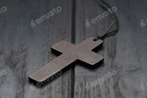 Preview: Christian cross on black wooden table, closeup