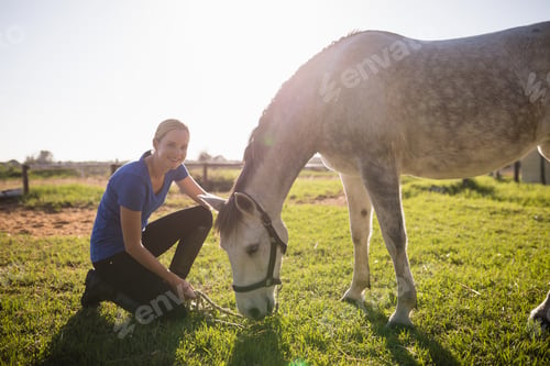 Preview: Portrait of smiling jockey stroking horse at barn