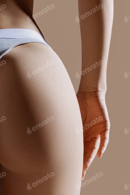 Preview: Perfect women's buttocks in gray lingerie close-up on beige background