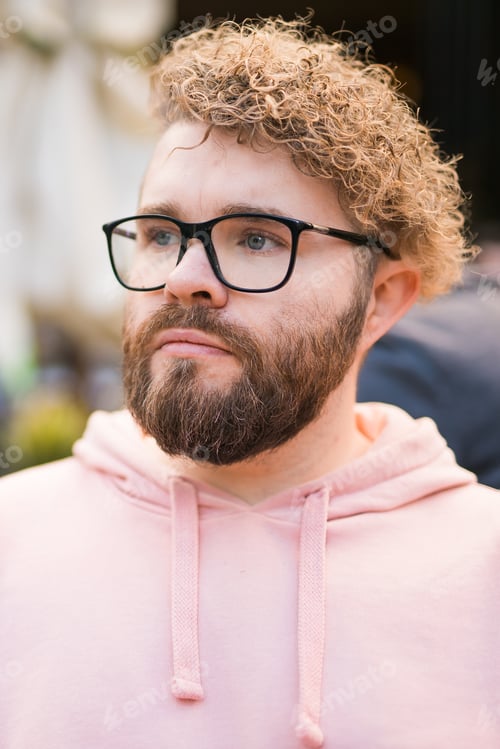 Preview: Millennial bearded man having breakfast at table of street cafe on spring day, drinking warm