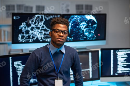 Preview: Contemporary young programmer standing by workplace