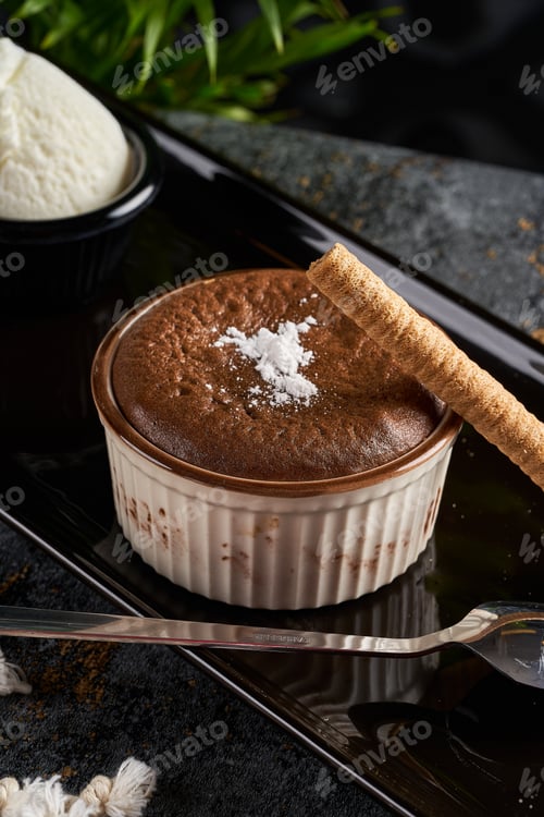 Preview: A close-up photo of a soufflé with biscuits on a black plate