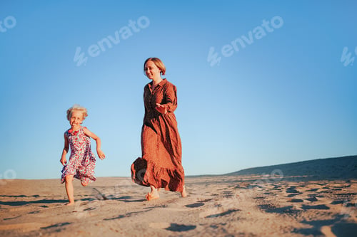 Preview: Happy mother and child run in desert and play catch-up, people in the beach