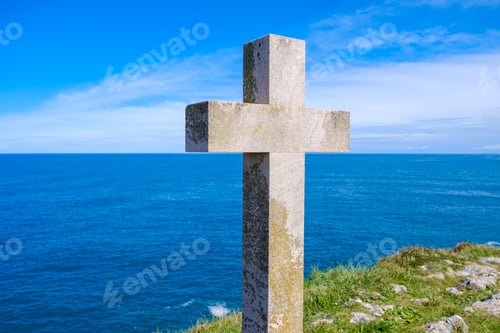 Preview: A Christian cross stands prominently on a hill, overlooking the vast expanse of the ocean.