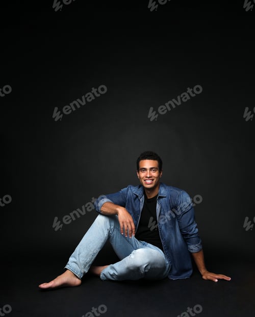 Preview: Handsome young African-American man sitting on black background