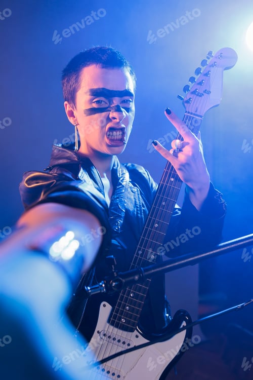 Preview: Playful guitarist showing rock sign on camera