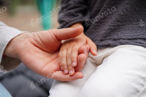 Preview: an adult's hand gently holding a child's hand, symbolizing care, trust, and connection