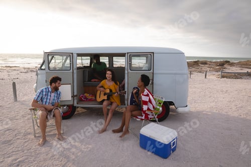 Preview: Friends enjoying at beach while standing near camper van on sunny day