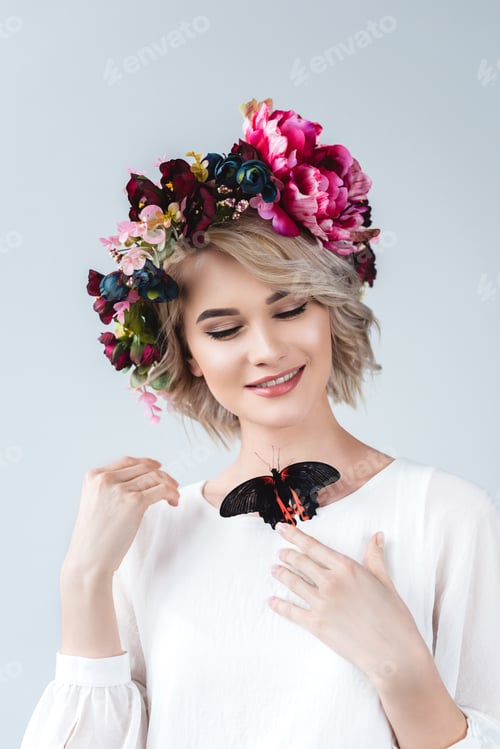 Preview: smiling girl posing in flower wreath with alive butterfly on neck, isolated on grey