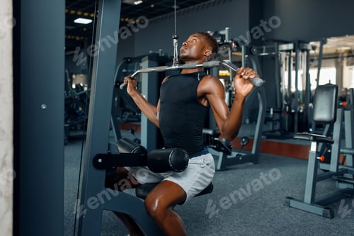 Preview: Muscular man in sportswear at exercise machine