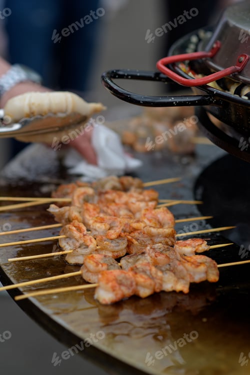 Preview: Cooking shrimp, prawn skewers on grill at street food festival - close up