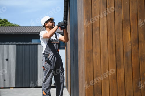 Preview: Construction worker installing wooden panels on prefabricated building