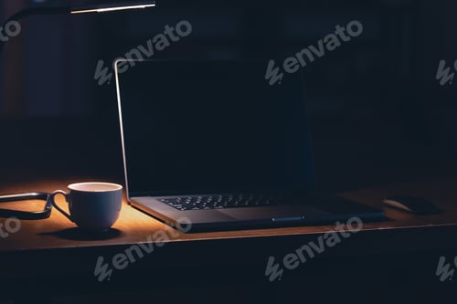 Preview: Workplace in the office with laptop and coffee in the dark room at night.