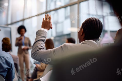 Preview: Rear view of black businessman asking a question on a conference in board room.